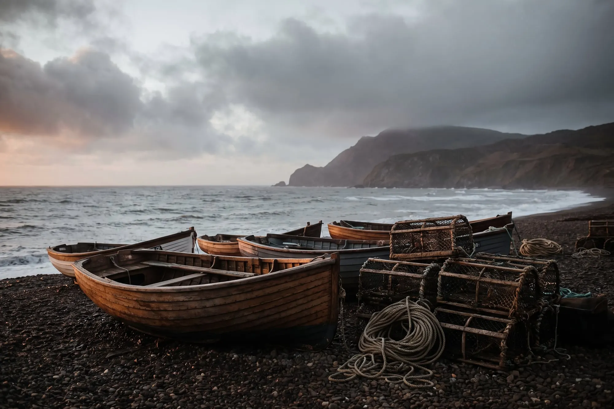 Wooden fishing boats and lobster pots on a shingle beach at first light