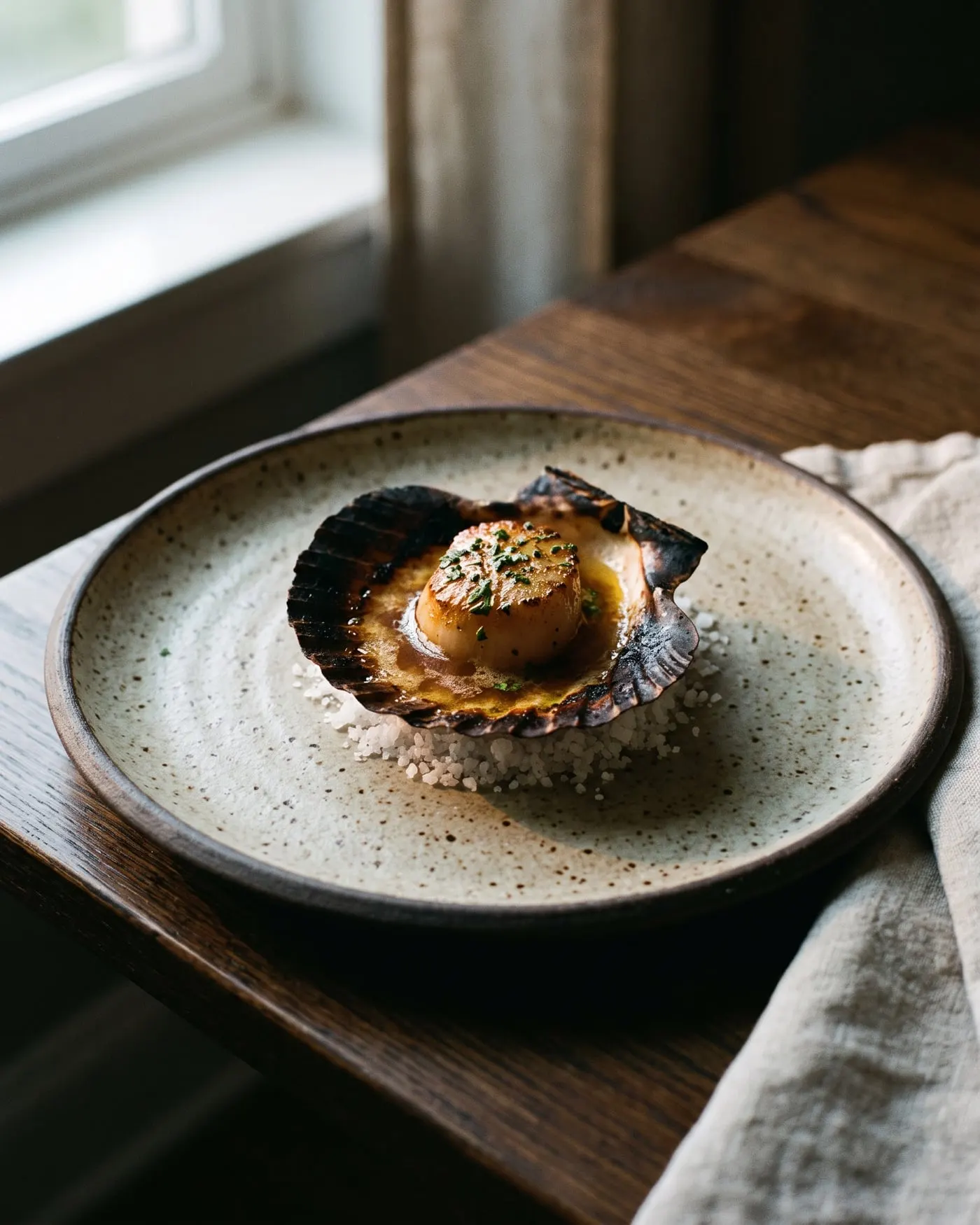 A scallop in its charred shell with brown butter and sea herbs