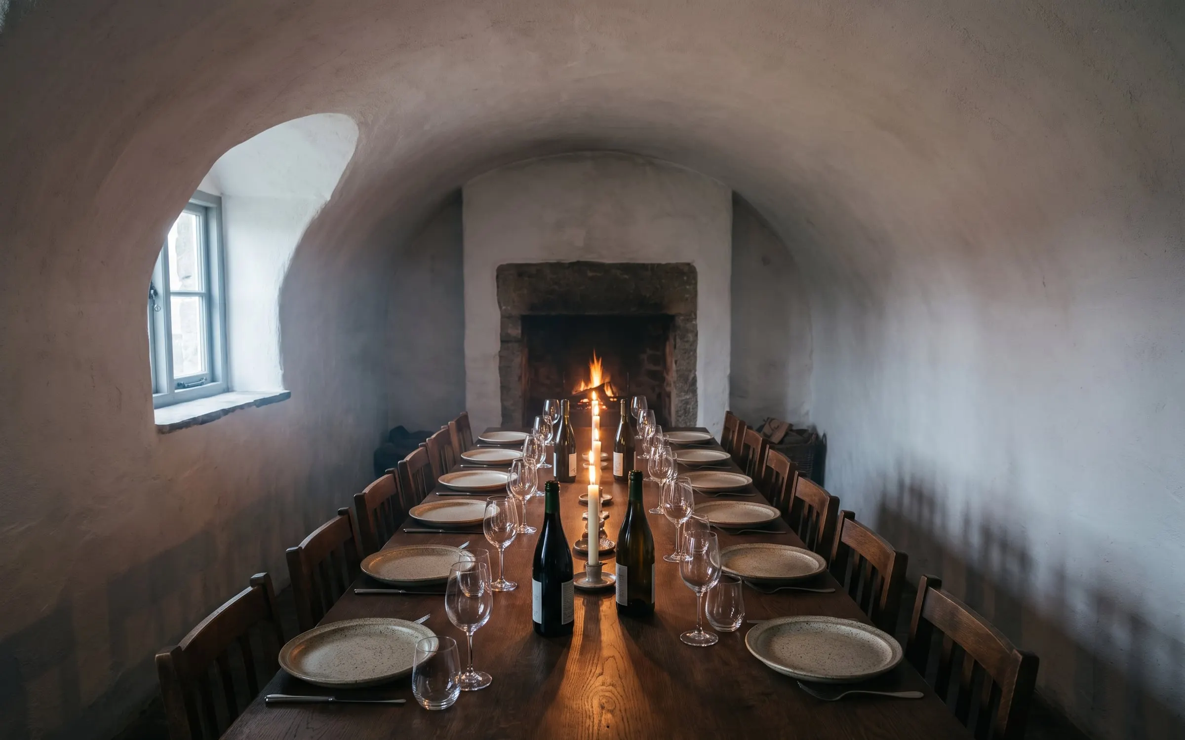 The vaulted cellar room with one long table laid for a private dinner